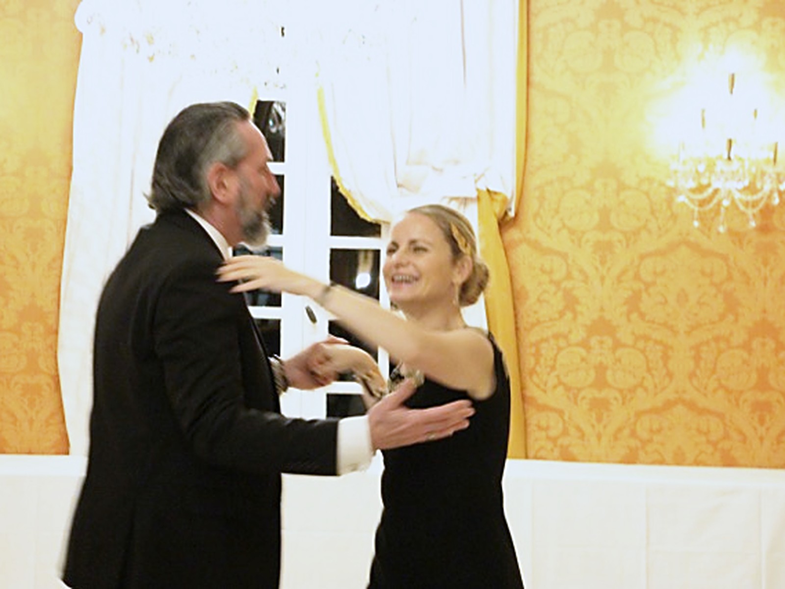 A couple dancing together in a candlelit ballroom during a milestone celebration