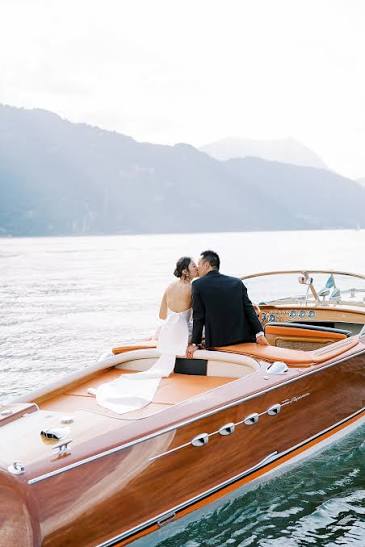 A couple aboard a wooden boat on a lake at dusk before a celebration weekend