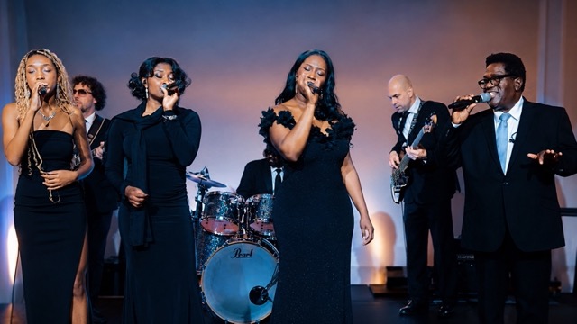The full ensemble performing at a wedding reception as guests fill the floor