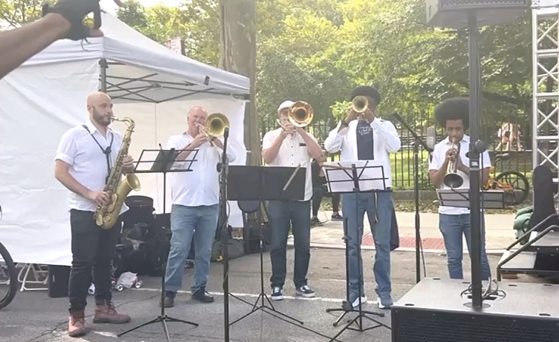The Gordon Dukes Music Company horn section — saxophone, trombone and trumpets — playing on the street at NYC Summer Streets