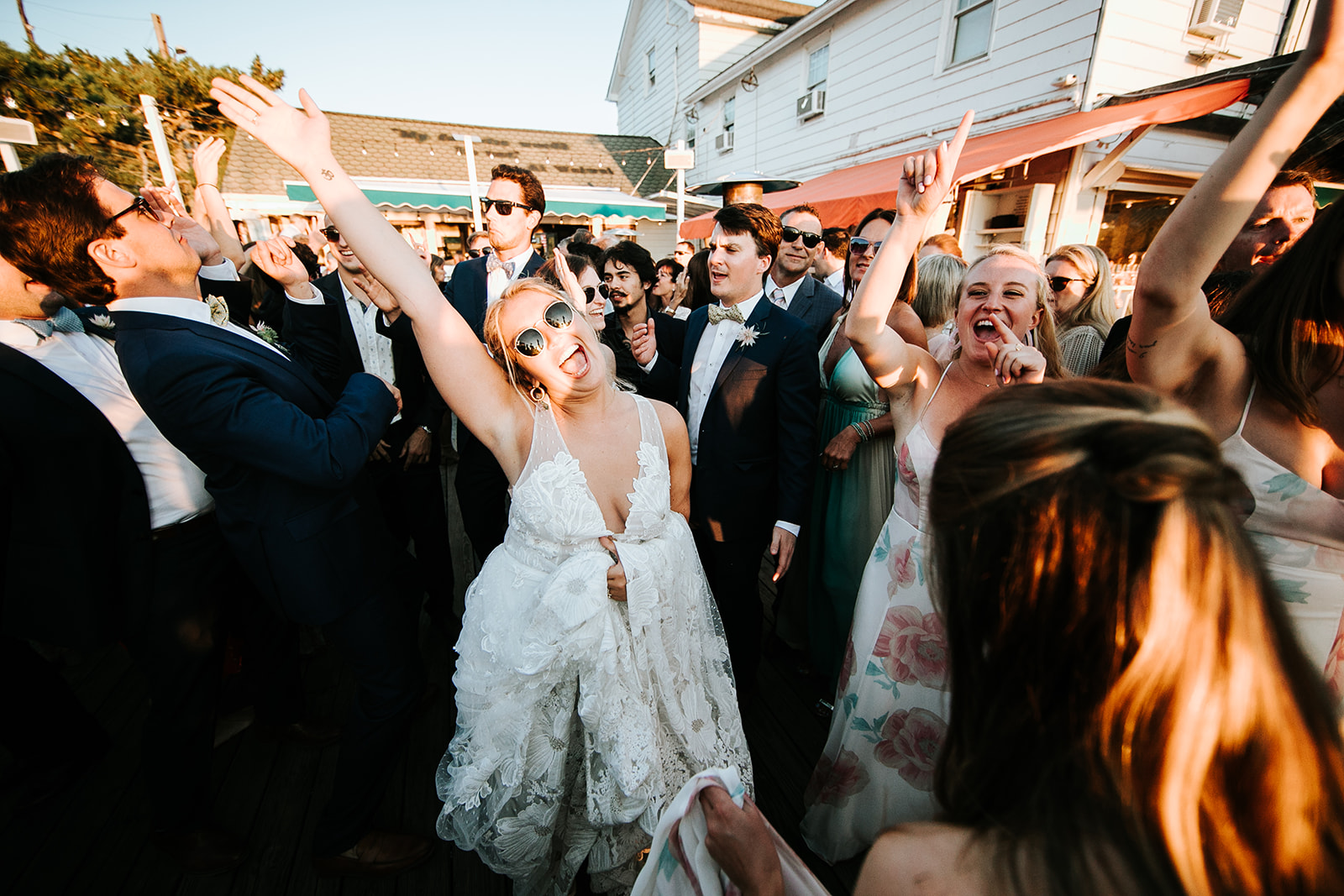 Bride mid-dance, hands raised, wearing sunglasses