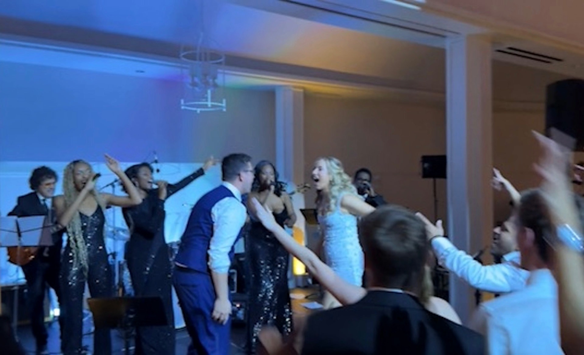 The Best Wedding Band on stage with guests dancing directly in front of them in the Hampton Bays ballroom