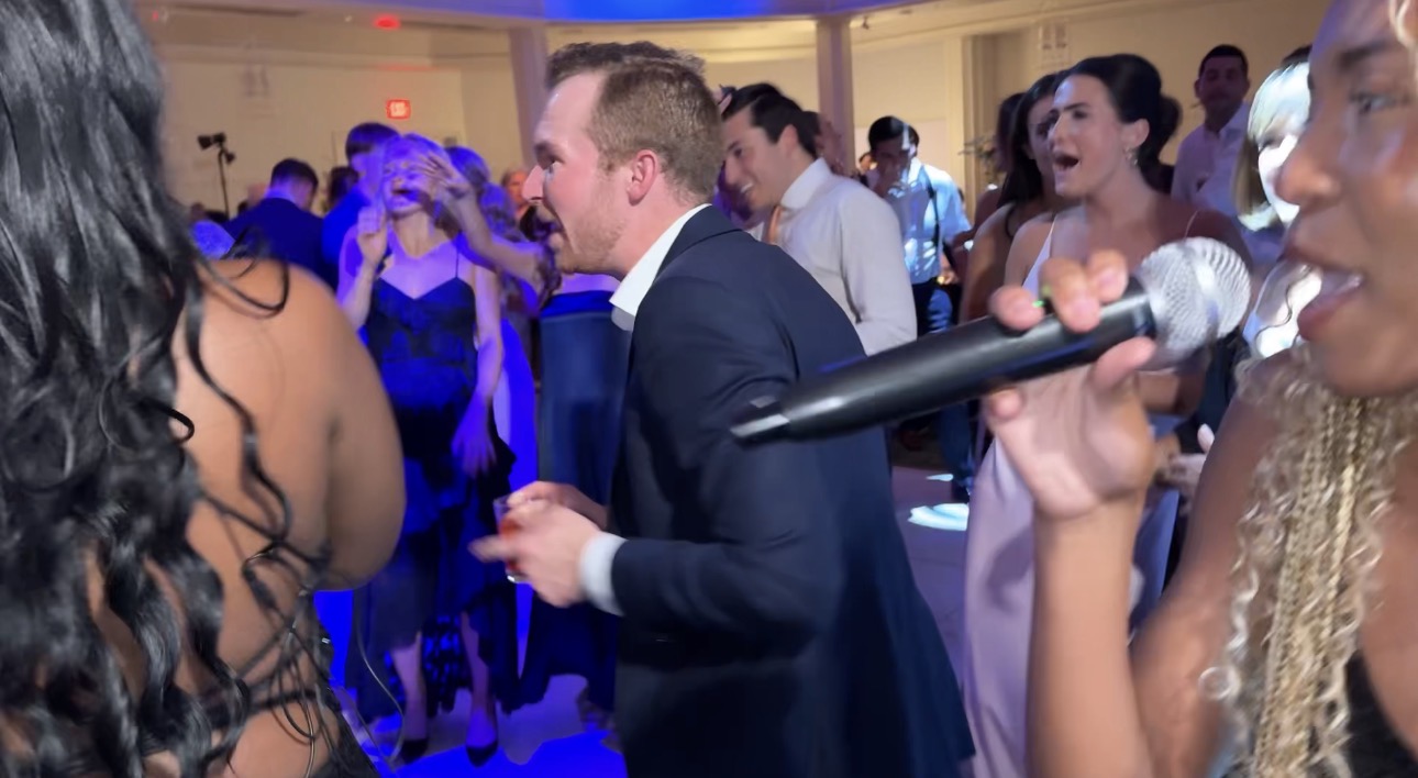 A vocalist holding a microphone among the guests on the dance floor