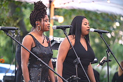 Two Gordon Dukes Music Company vocalists singing into microphones at an outdoor performance
