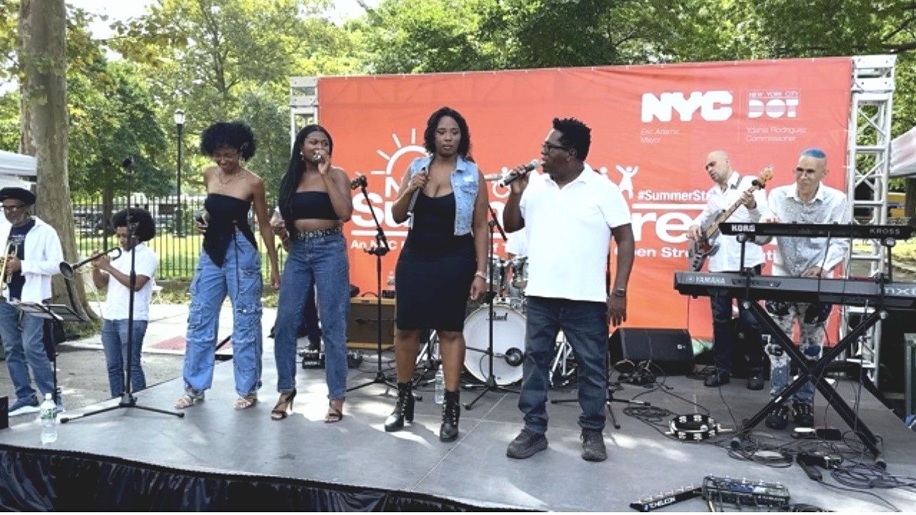 Gordon Dukes and the company's vocalists performing on the NYC Summer Streets stage