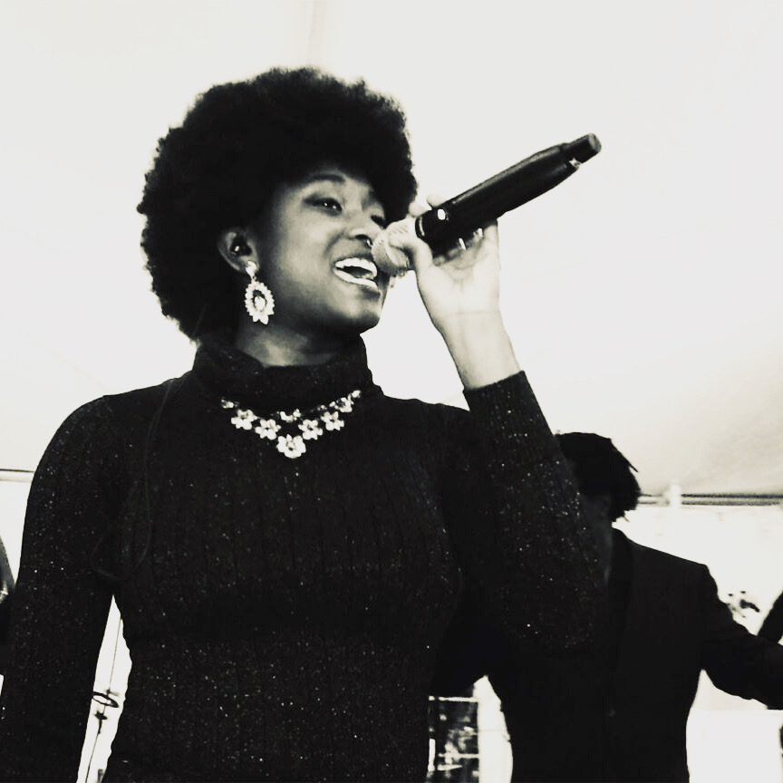 Alexandra Dukes of Gordon Dukes Music Company singing into a handheld microphone, black and white