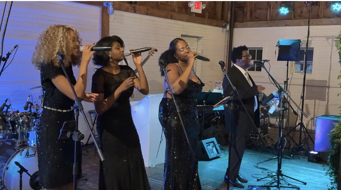 Gordon Dukes Music Company vocalists and rhythm section performing together on a barn stage