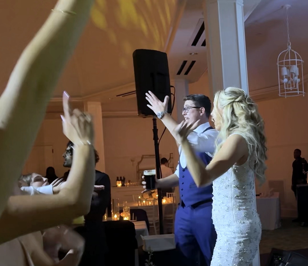 Katherine and Kevin with their hands in the air among guests as the reception reaches full celebration