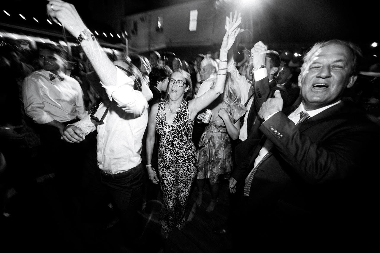 Guests with hands raised, mid-dance, black and white