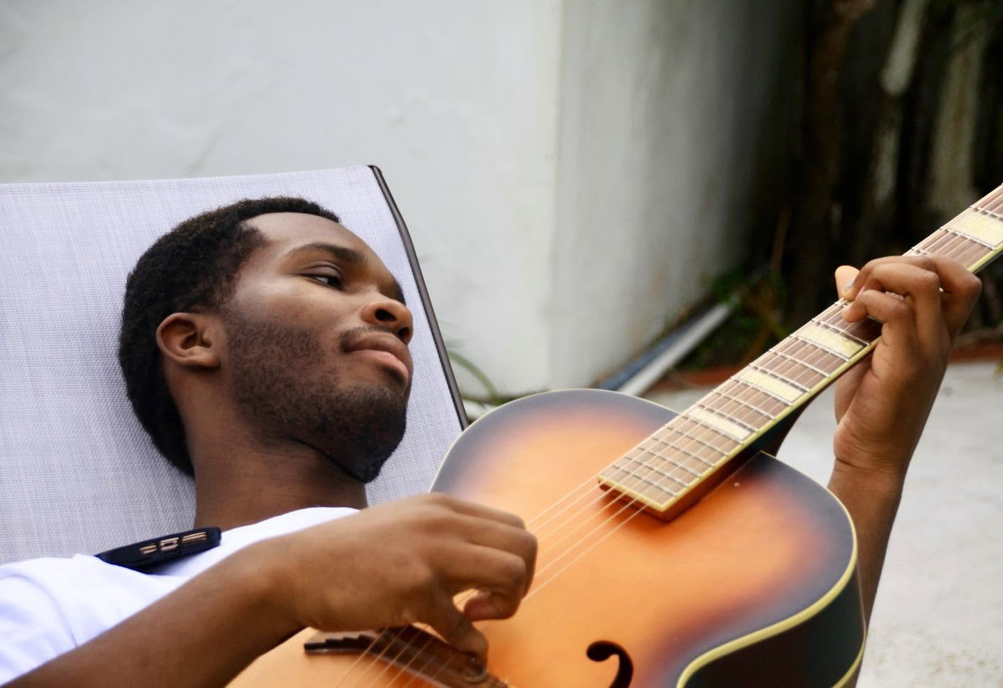Dylan Dukes playing an archtop guitar in daylight