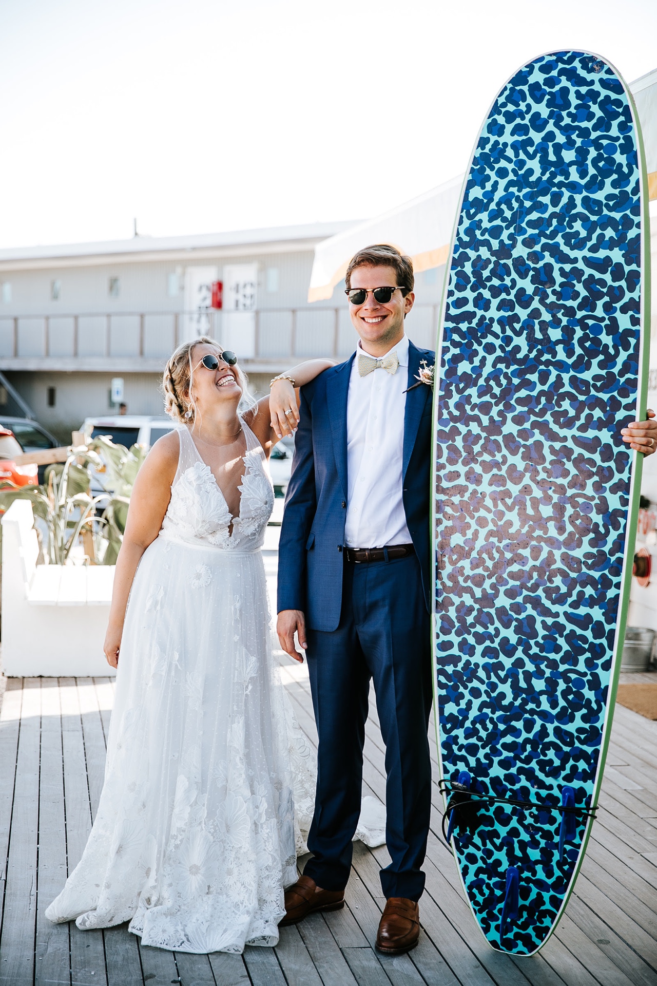 Bride and groom laughing beside a surfboard at The Surf Lodge, Montauk
