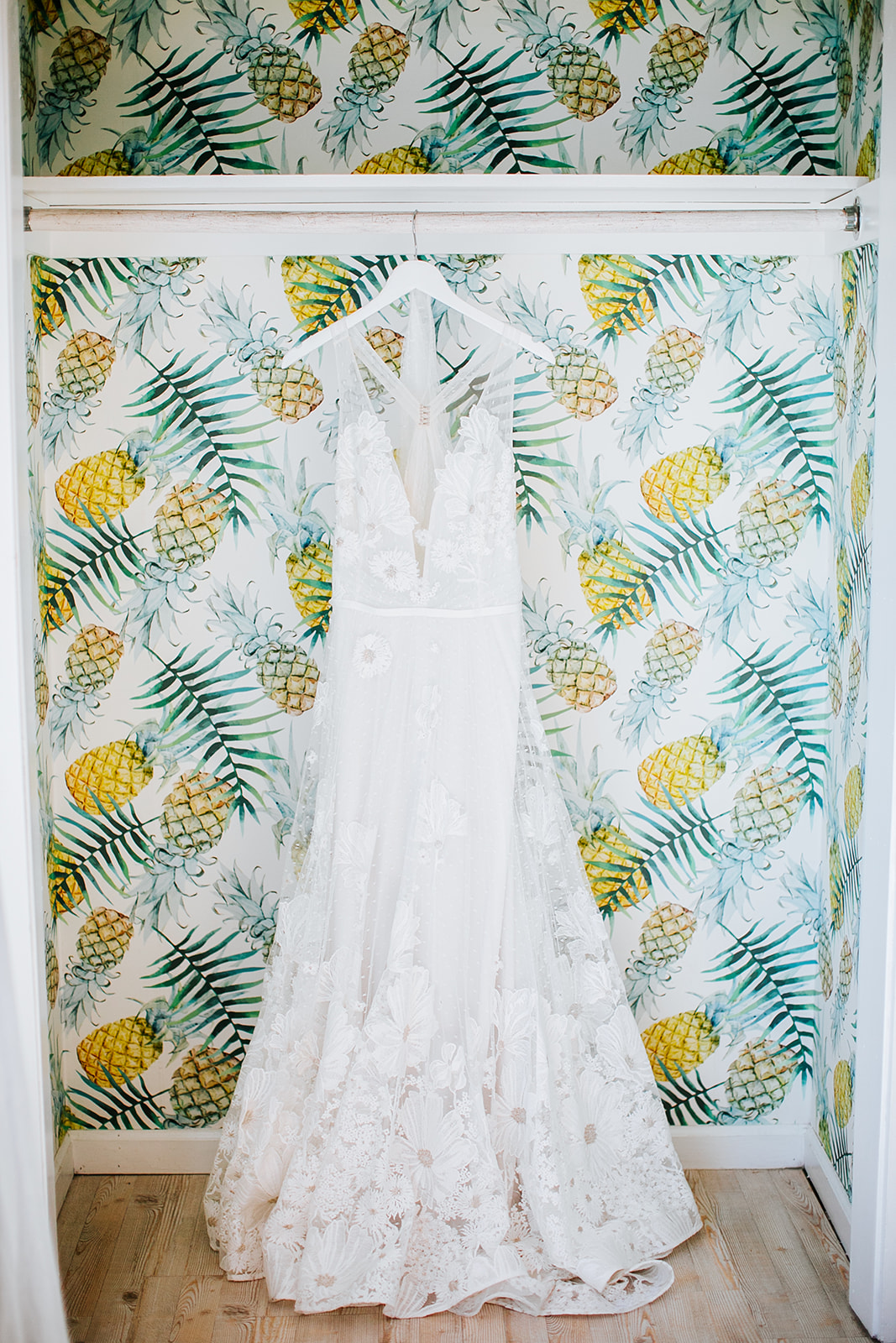 Bride's dress hanging against a pineapple-print wall