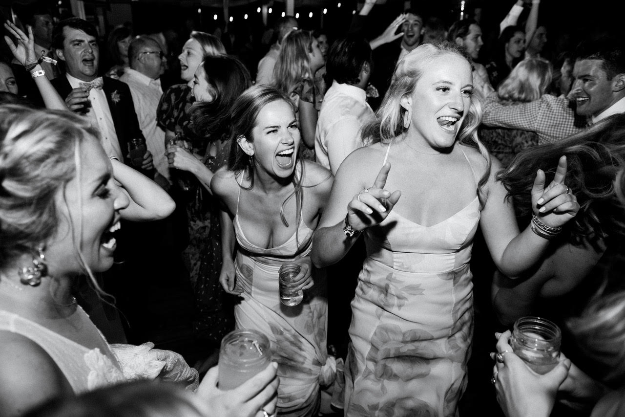 Bridesmaids laughing on the dance floor in black and white